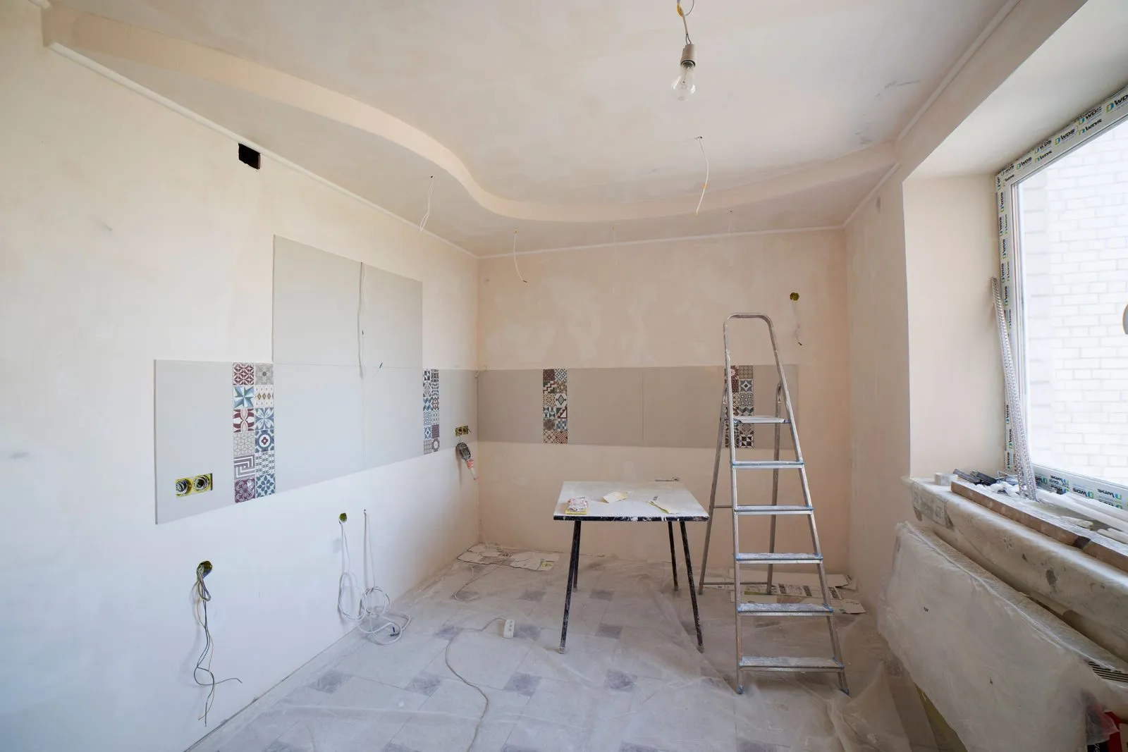 Kitchen reno in progress with plastered walls and a ladder, tagged drywall, ladder, window and floor 2