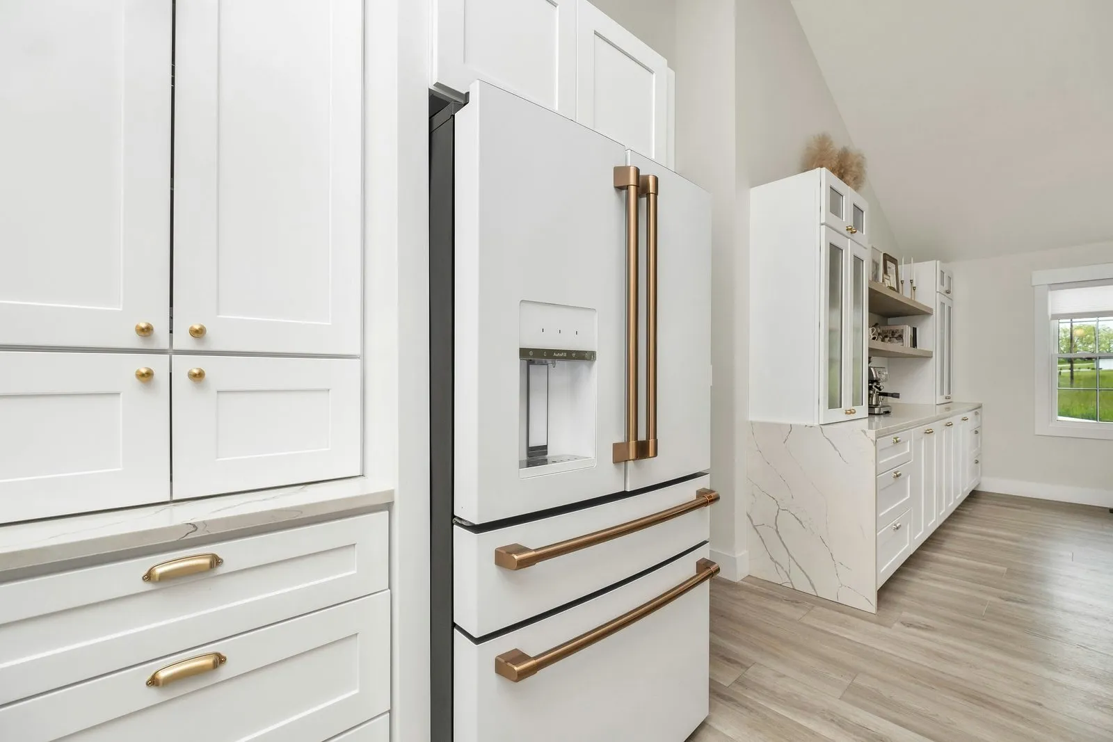 Brass hardware on white cabinets and fridge