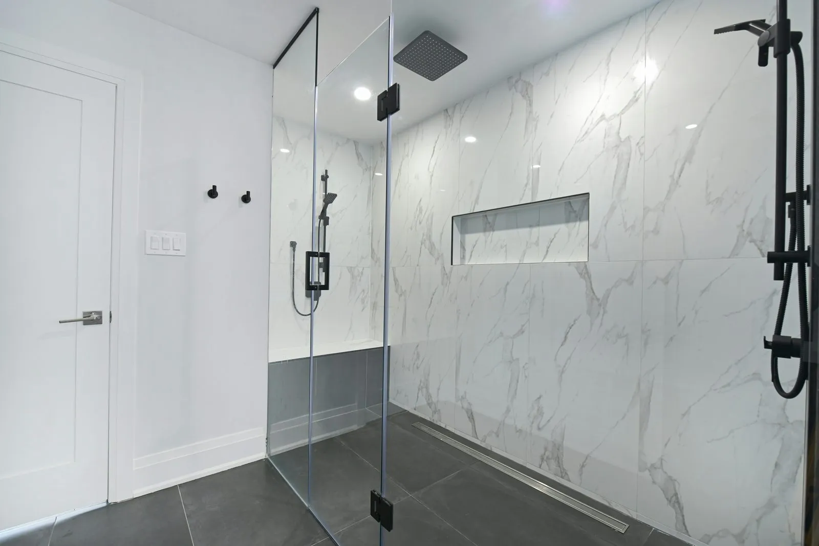 Walk-in glass shower with marble-look tile